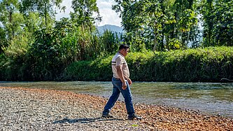 Aníbal steht am Fluss neben seines Hauses 