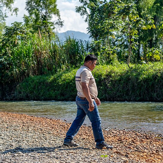Aníbal steht am Fluss neben seines Hauses 