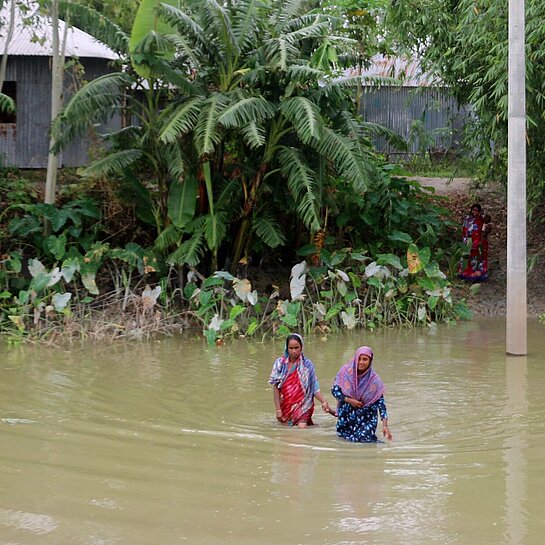 Zwei Frauen waten durch hohes Wasser