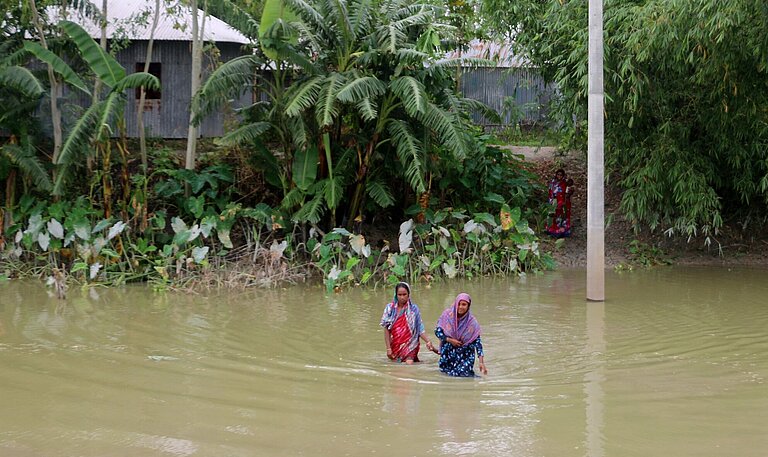 Zwei Frauen waten durch hohes Wasser