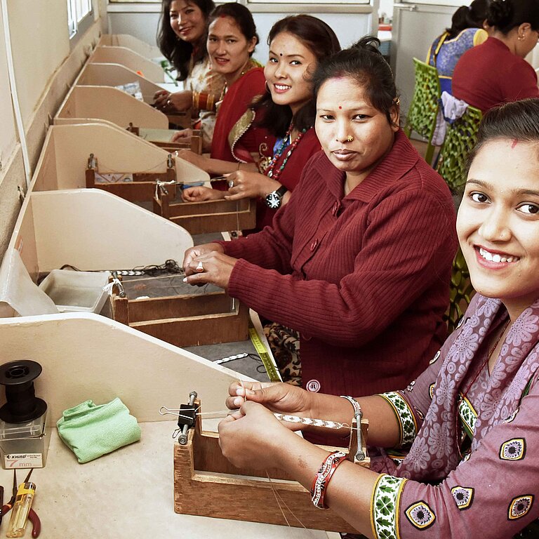 Frauen der Kooperative „Beads for Life“ in Nepal bei der Handarbeit.