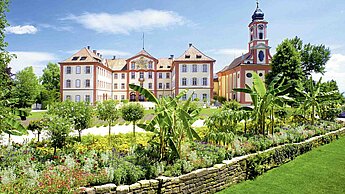 Blick auf ein prachtvolles Schloss in einem üppig grünen Garten