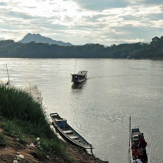 Menschen und Fähren am Mekong