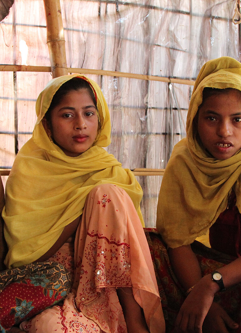 Vier Rohingya Mädchen sitzen auf dem Boden.