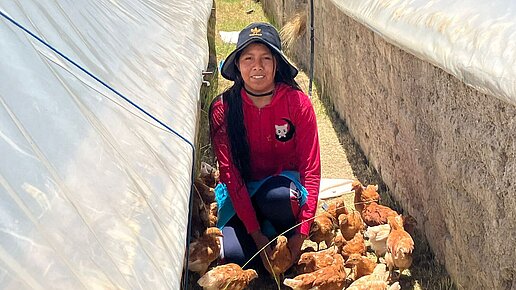 Junge Frau sitzt zwischen Hühnern