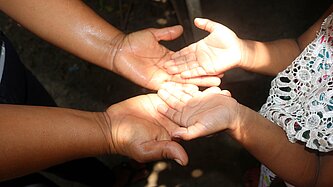 Kinderhände liegen mit den Handinnenflächen nach oben in den Händen einer Erwachsenen Person