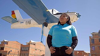 Eine junge Frau steht vor einem Kleinflugzeug