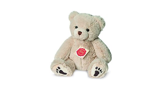 Sitzender Plüschtierteddy in wollweiß mit braunen aufgestickten Tatzen.