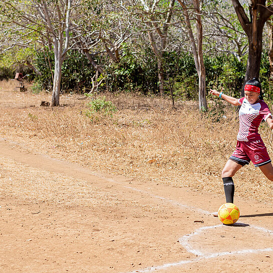 Eine junge Frau im roten Fußballtrikot holt aus zum Eckschuss.