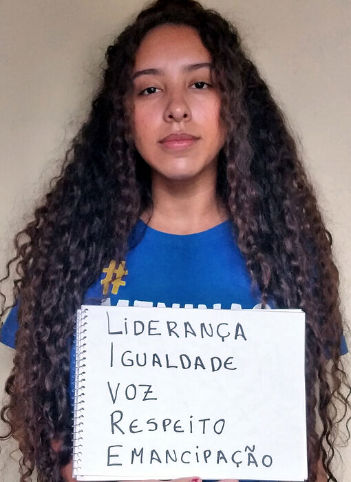 Mädchen aus Brasilien fordern: Leadership, Gleichberechtigung, Mitbestimmung, Respekt und Unabhängigkeit. Eine junge Frau hält einen Block mit Forderungen.