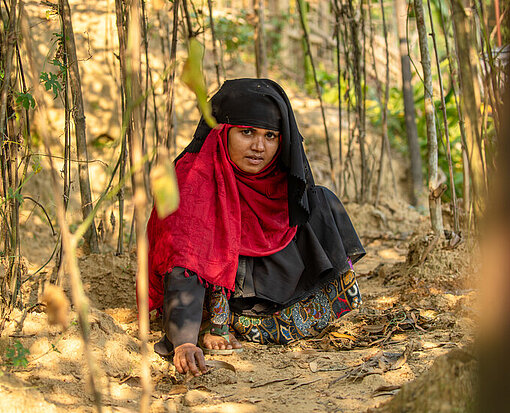 Yasmin hockt in ihrem Garten in Bangladesch