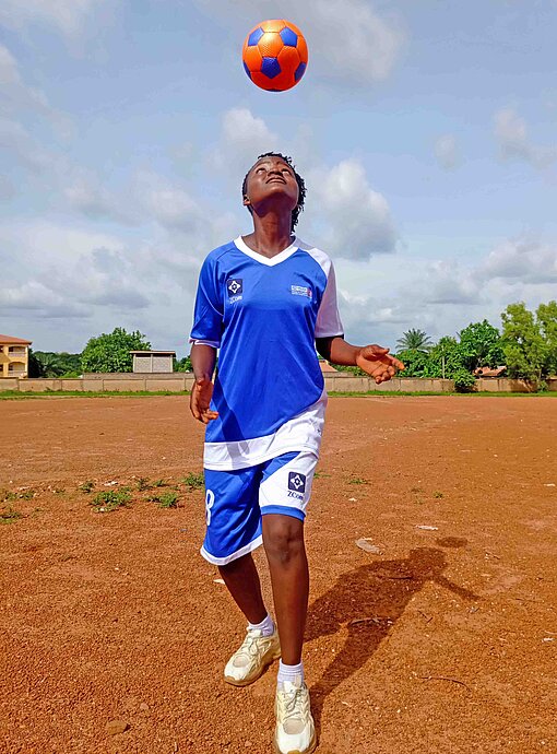Mädchen sollen auch im Süden von Guinea gleichberechtig aufwachsen und ihr Leben selbstbewusst gestalten können Ein Mädchen mit Fußballtrikot kickt einen Ball in die Luft