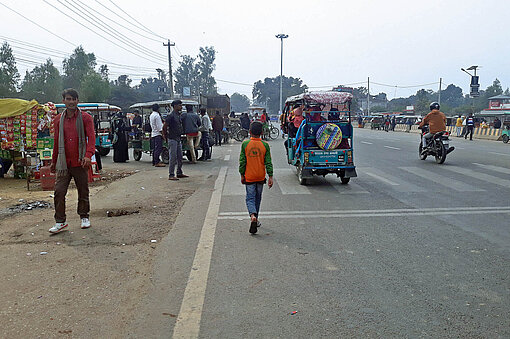 An einer Hauptstraße im Bezirk Banke im Südwesten von Nepal Menschen laufen entlang einer Straße