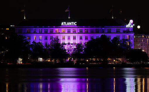 Das Hamburger Hotel Atlantic setzte 2025 ein leuchtendes Zeichen für Mädchenrechte Fassade des Hamburger Hotel Atlantic an der Binnenalster bei Nacht in pink beleuchtet