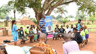 Junge Menschen mit Lehrenden sitzen draußen im Kreis und nehmen an einer Schulung teil