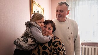 Yuri und Nadia zusammen mit eines ihrer Pflegekinder in den Armen in ihrem Haus