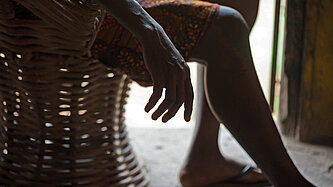 Man sieht die Hand einer Frau, die schlaff auf einem Stuhl sitzt
