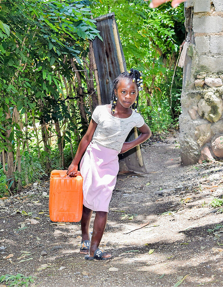 Ein Mädchen trägt einen großen Wasserkanister