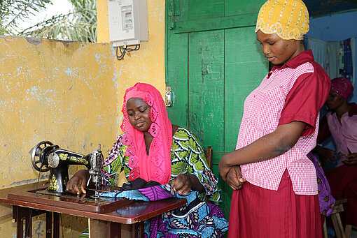 Roumana lernt neue Nähtechniken von ihrer Kollegin Zwei Mädchen aus Togo mit Nähmaschine