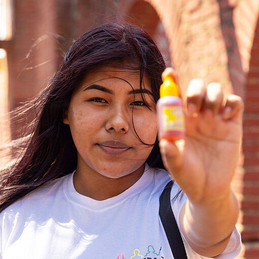 Eine junge Frau hält eine kleine Flasche in die Kamera