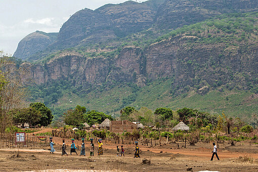 Frauen laufen zum neuen, von Plan International unterstützten Gesundheitszentrum im guineischen Kindia Eine spektakuläre Berglandschaft mit Frauen in Guinea
