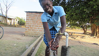 Handwaschstationen für Schulen in Malawi. Eine junge Frau wäscht sich die Hände an einer Handwaschstation.