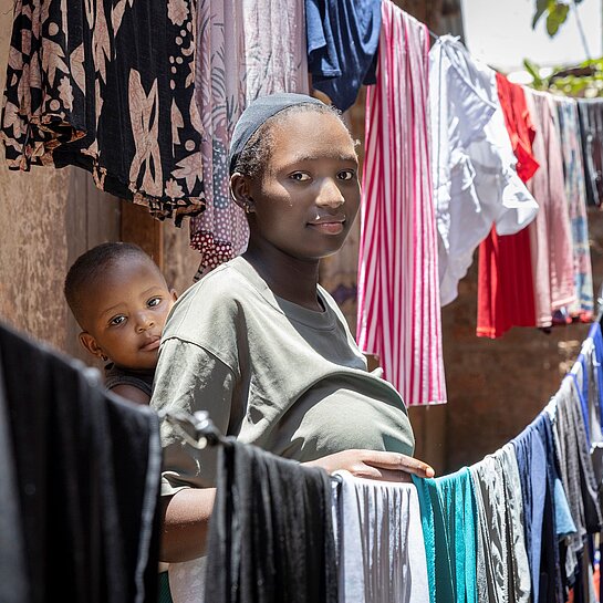Faith mit ihrer Tochter in einer Gasse neben ihrem Zuhause stehend