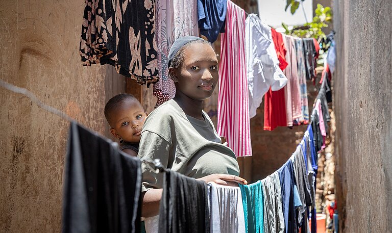 Faith mit ihrer Tochter in einer Gasse neben ihrem Zuhause stehend