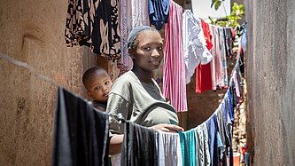Faith mit ihrer Tochter in einer Gasse neben ihrem Zuhause stehend
