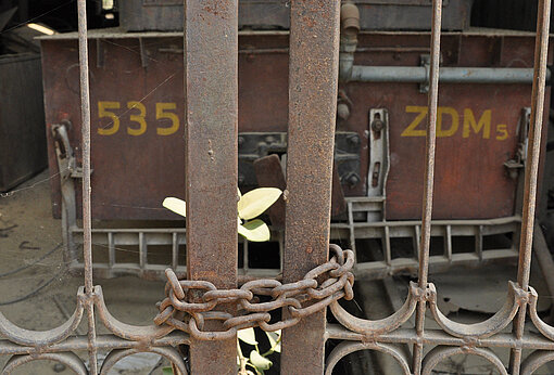 Wagon hinter einem mit einer Kette verschlossenen Tor.