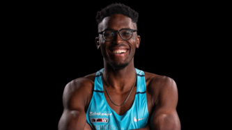 Leichtathlet Endiorass Kingley trägt sein Laufshirt und lacht mit verschränkten Armen. Er trägt eine Brille.