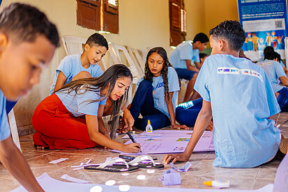 Junge Menschen gestalten gemeinsam ein Plakat