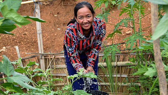 Win gießt den Gemüsegarten, den sie mithilfe von Plan International in der Nähe ihres Hauses angelegt hat.