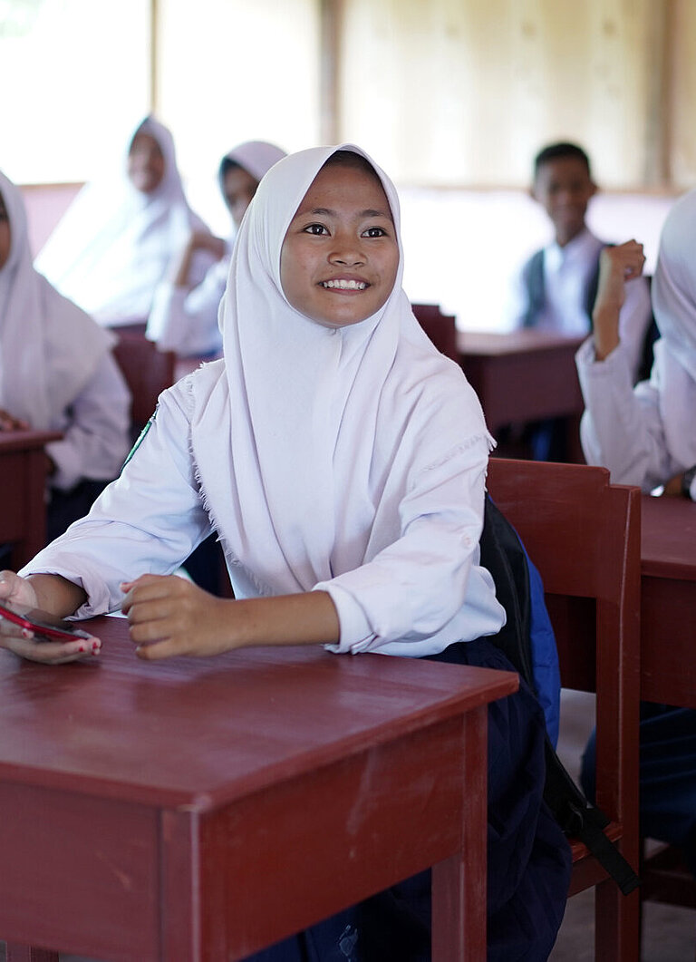 Afriyana sitzt mit anderen Schülerinnen in einem Klassenraum.