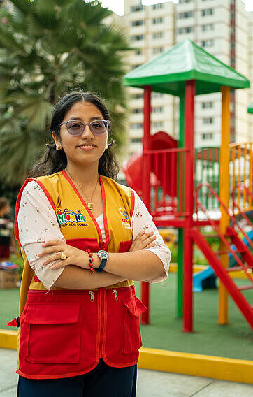 Als Koordinatorin eines Jugendbeirats setzt sich Joselyn auch für Kinderrechte ein Eine junge Frau steht mit verschränkten Armen und selbstbewusstem Blick vor einem Spielplatz