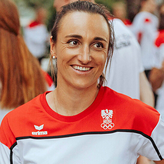 Eine Frau mit Sporttrikot steht zusammen mit anderen Personen in Trikots und lächelt in die Kamera