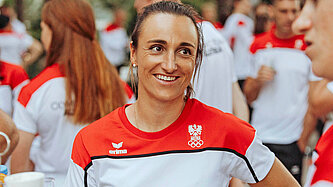 Eine Frau mit Sporttrikot steht zusammen mit anderen Personen in Trikots und lächelt in die Kamera