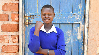 Die 14-jährige Hellen in Tansania steht vor einer Eingangstür