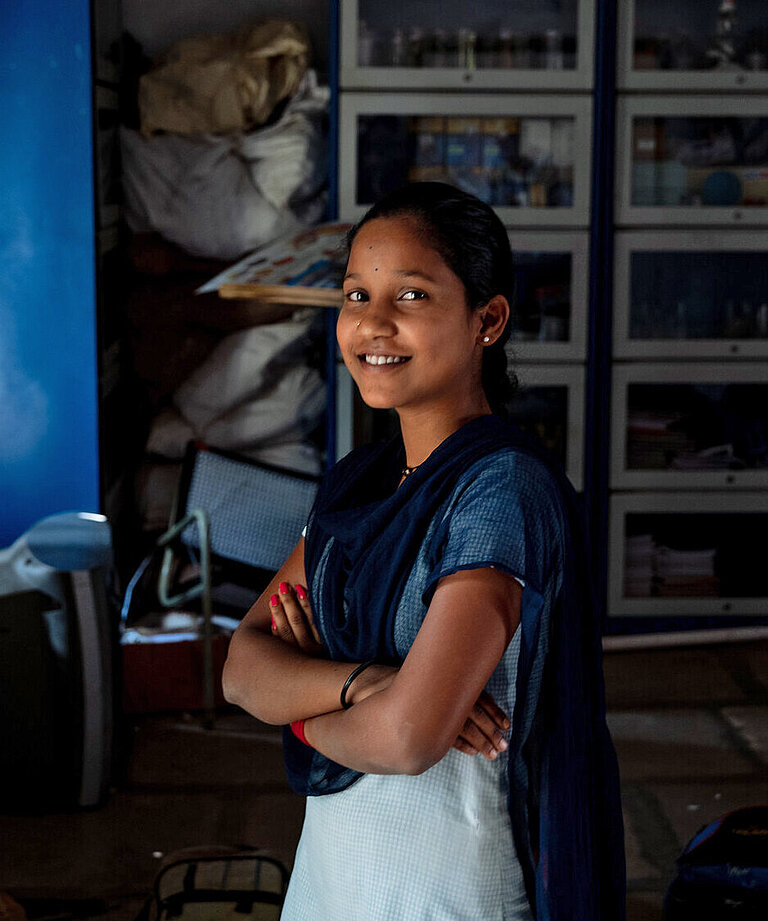 Ein Mädchen steht im Plan-Büro in Indien vor Regalen mit Akten