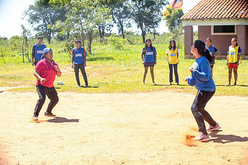 Kinder der Gemeinde aus Paraguay stehen draußen und spielen auf einem Platz Fußball
