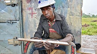 Ein junger Mann sitzt vor einer Werkstatt in Guinea