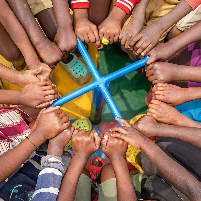 Viele Arme von Kindern ergreifen eine Haltestange in der Mitte eines Karussells