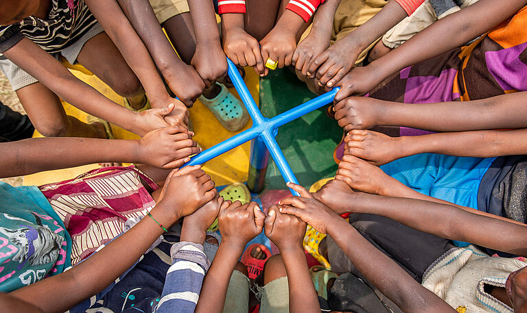 Viele Arme von Kindern ergreifen eine Haltestange in der Mitte eines Karussells