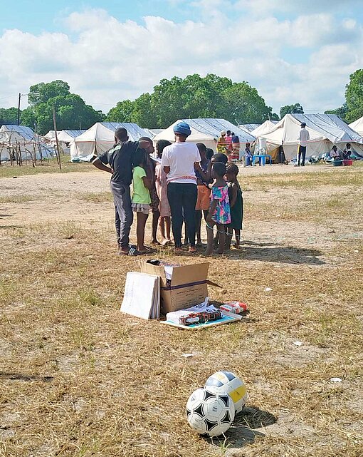 Auf einem sandigen Platz spielen Kinder Fußball