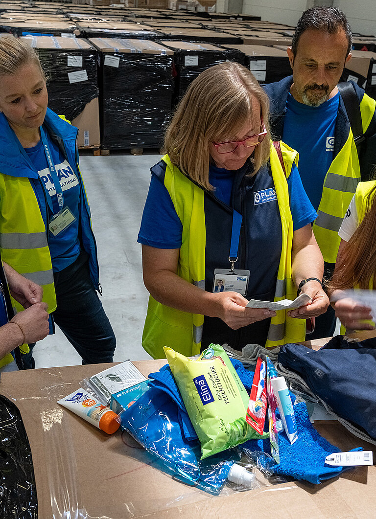 Mitarbeitende von Plan International begutachten ein Dignity Kit