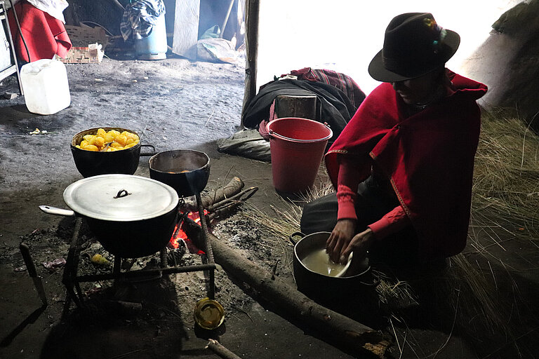 Indigene Ecuadorianerin vor einer Kochstelle