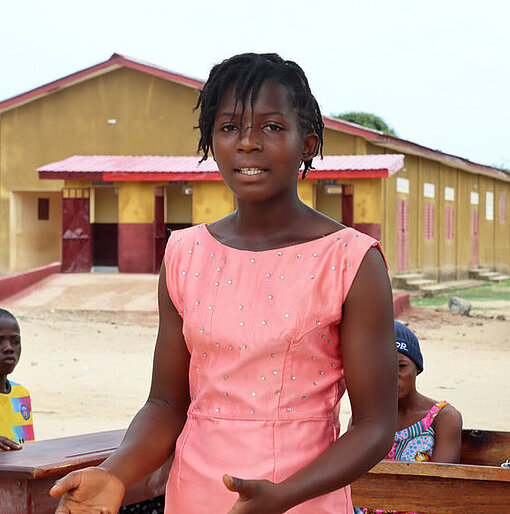 Eine junge Frau steht vor einer Gruppe Jugendlicher und redet