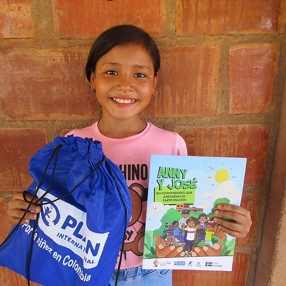 Ein Mädchen hält einen Plan-Turnbeutel und ein Heft in der Hand