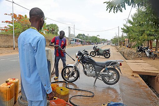 Zwei Männer stehen an einer Fernstraße und reparieren Motorräder