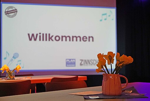 Blick auf ein Blumengesteck und eine Bildschirmleinwand